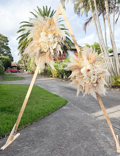 Outdoor wedding ceremony decor with pampas grass and sola peony floral arrangements, styled for modern neutral weddings.