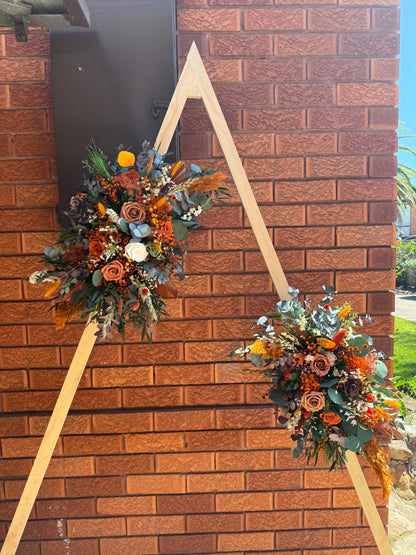 Boho wedding arbor decorated with large dried flower arrangements in burnt orange, rust and natural tones.