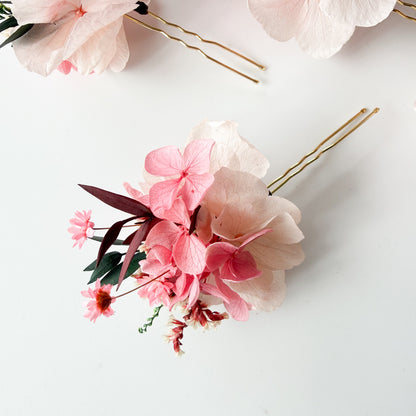 Floral hair accessories with pink flowers and gold bobby pins on a white background