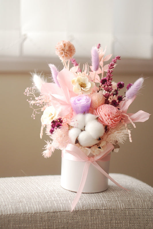 Pink and purple dried flower arrangement in a round white box with cotton, sola flowers, and preserved florals. Ideal for birthday gift, office decor, or thank you present.


