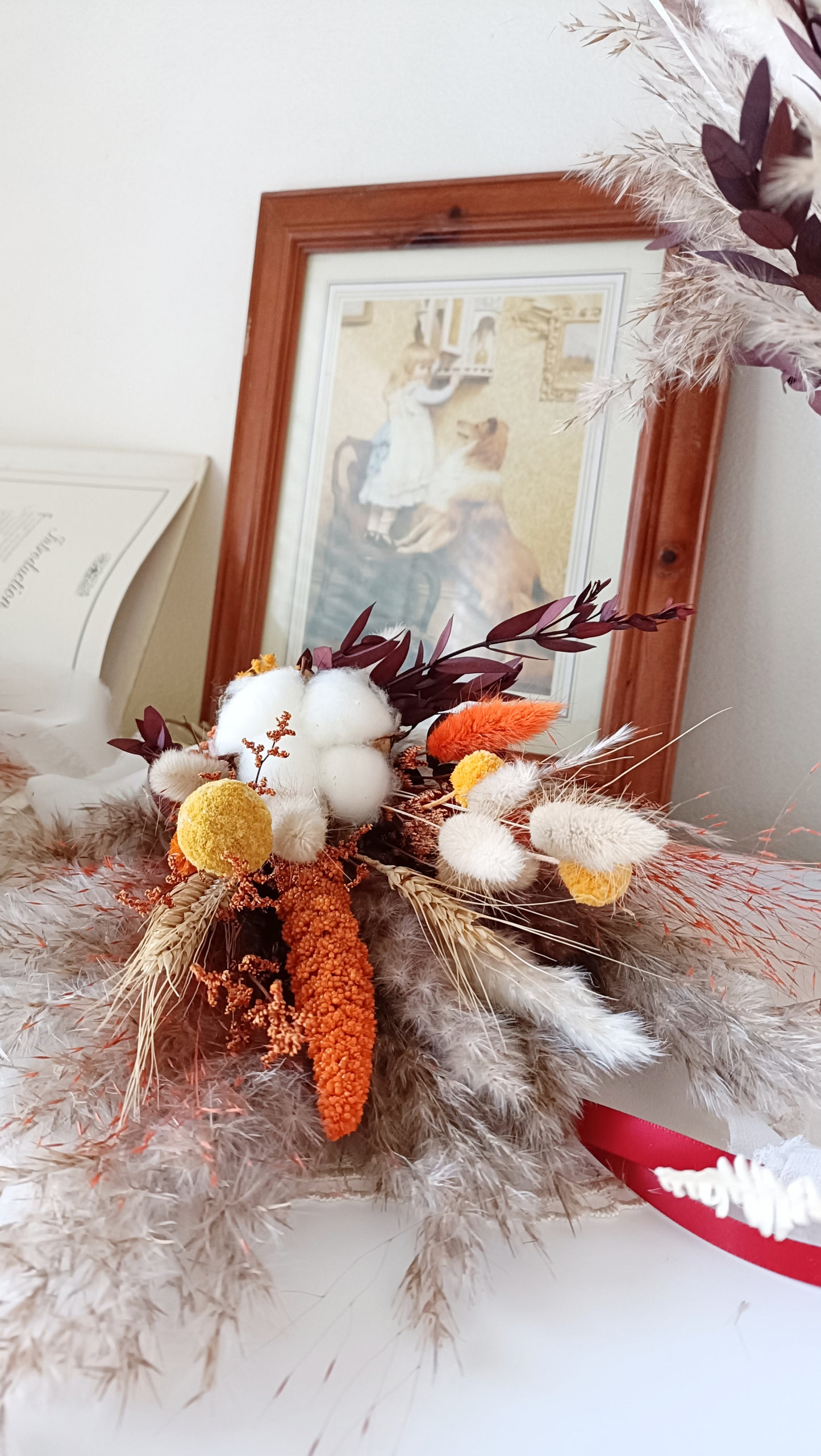 This eye-catching wedding bouquet features a bold combination of red, orange, and natural hues, crafted from a selection of dried flowers. The arrangement includes pampas grass, preserved foliage, and textured accents, offering a rustic yet vibrant look perfect for autumn weddings. Long-lasting and full of character, this bouquet adds a fiery touch to any bridal ensemble. Explore our collection for more unique and seasonal wedding bouquets.