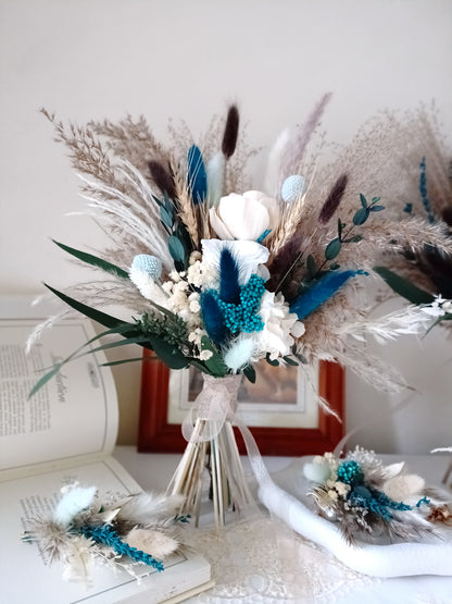 This handcrafted wedding bouquet features an exquisite blend of dried flowers, combining soft natural tones with striking blue accents. The arrangement includes pampas grass, preserved foliage, and delicate bunny tails, creating a perfect balance of rustic charm and modern elegance. Ideal for a boho-themed wedding, this long-lasting bouquet adds a touch of timeless beauty to your special day. Explore our collection for more unique bridal bouquets and wedding decor ideas.