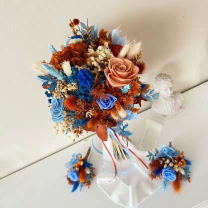 This beautifully crafted wedding bouquet features an elegant mix of orange, white, and natural tones, made from dried flowers and pampas grass. The arrangement exudes a modern rustic charm, with preserved foliage and delicate accents adding a sophisticated touch. Perfect for a contemporary bride, this long-lasting bouquet is ideal for weddings with a natural or bohemian theme. Explore our collection for more unique bridal bouquets and wedding decor inspirations