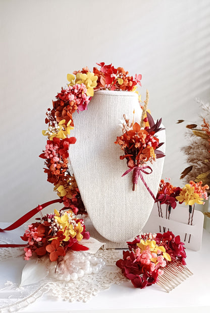 A delicate dried flower crown featuring a bold mix of red yellow & terracotta petals, adorned with tiny pearl accents. The wreath is tied with sheer ribbon, creating an elegant, romantic look for a wedding or special occasion.