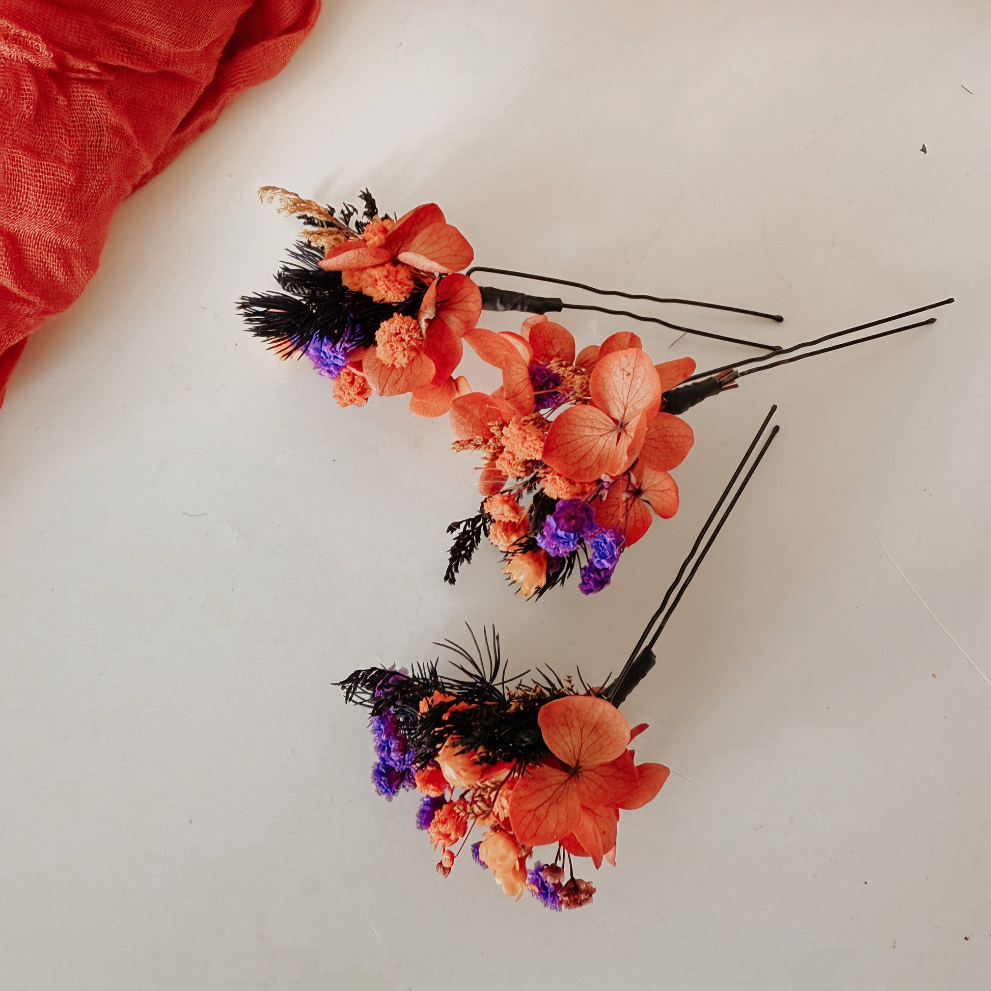 Set of dried flower hair pins in orange, purple and burgundy shades on neutral background — handmade bridal accessories for rustic weddings