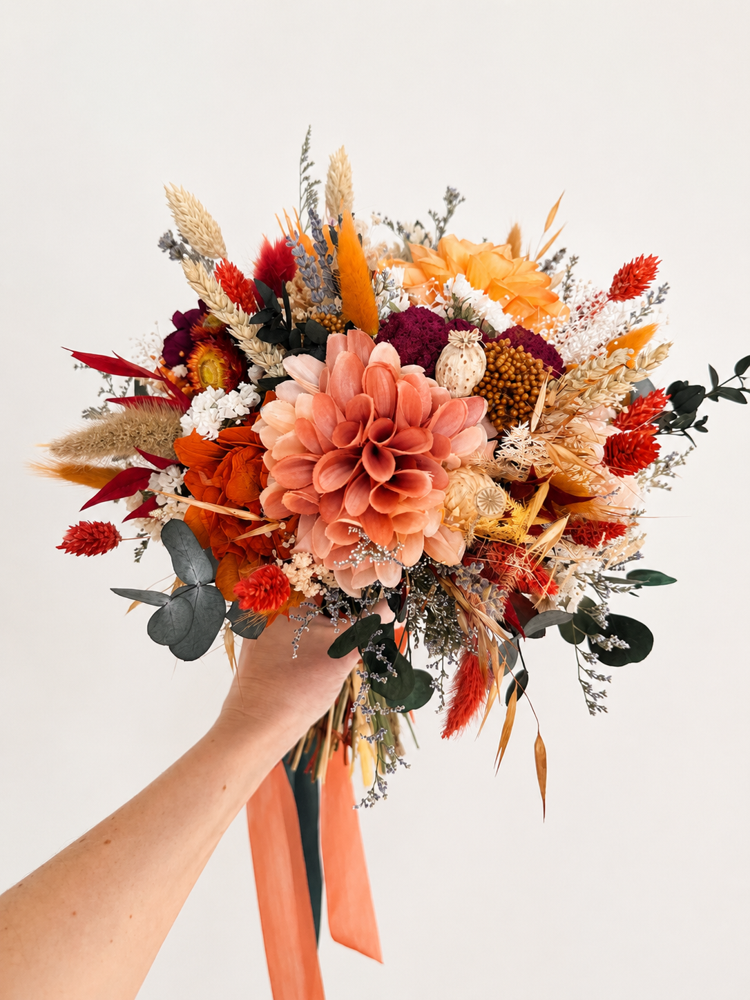 Side view of a preserved bridal bouquet featuring burnt orange dahlia, burgundy flowers, ivory accents and eucalyptus.