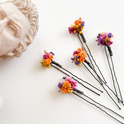 Small Colorful wedding floral hairpins on a white surface.