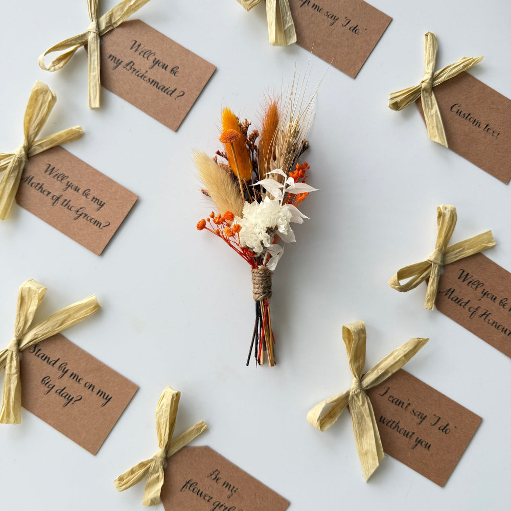 Small bouquet with dried flowers and tied with ribbons, surrounded by personalized tags on a light background.