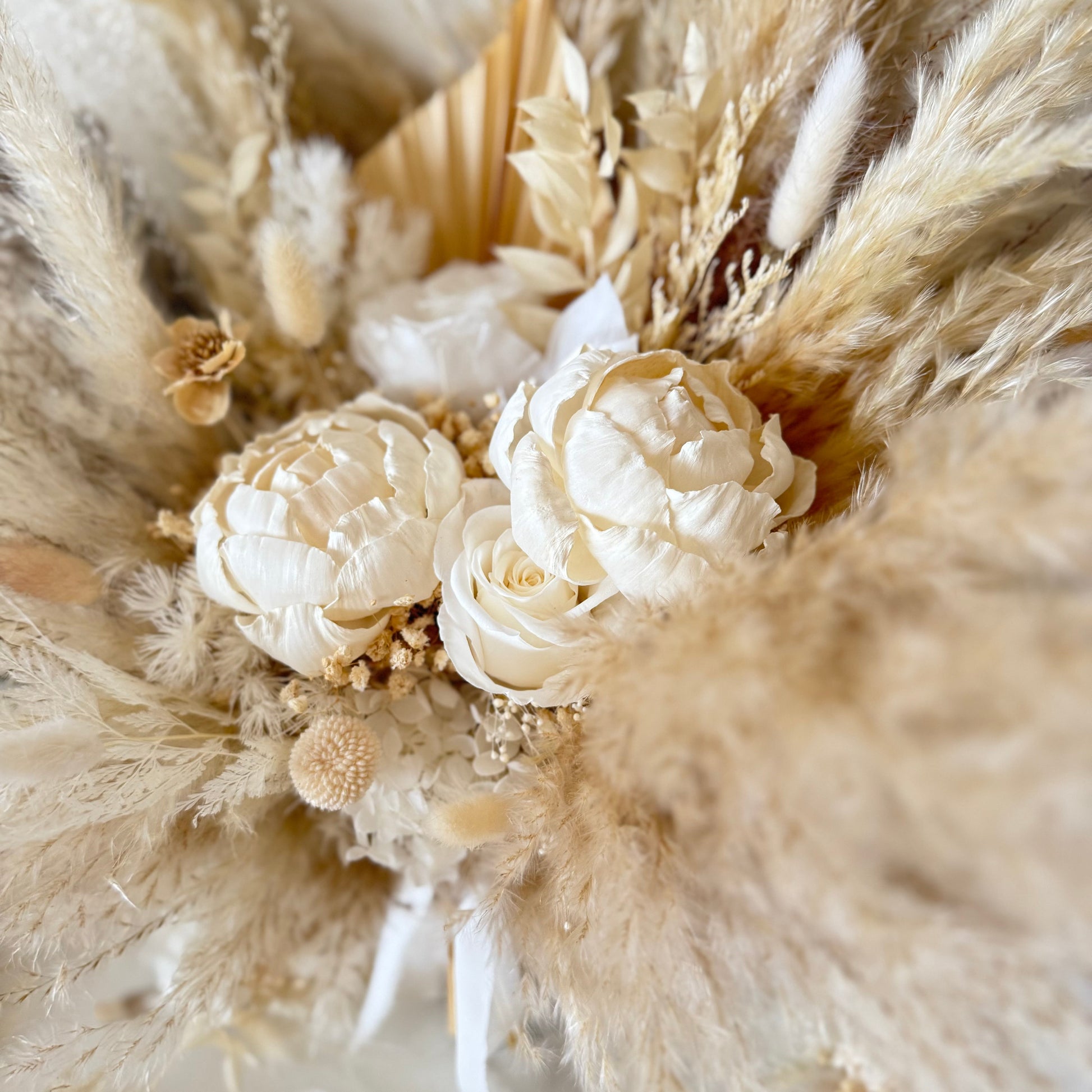 Close-up of a wedding bouquet featuring sola peonies and dried pampas grass, designed for timeless and neutral wedding styling.