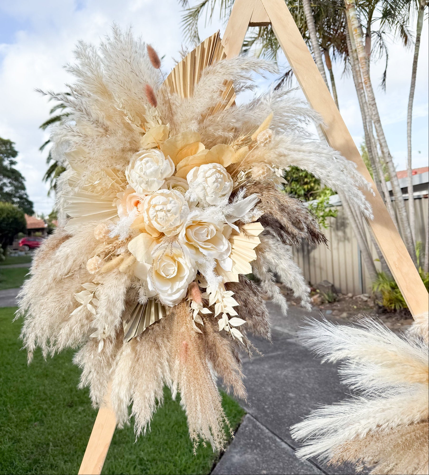 Wedding ceremony backdrop with pampas grass and sola peonies, styled in neutral tones for elegant outdoor celebrations.