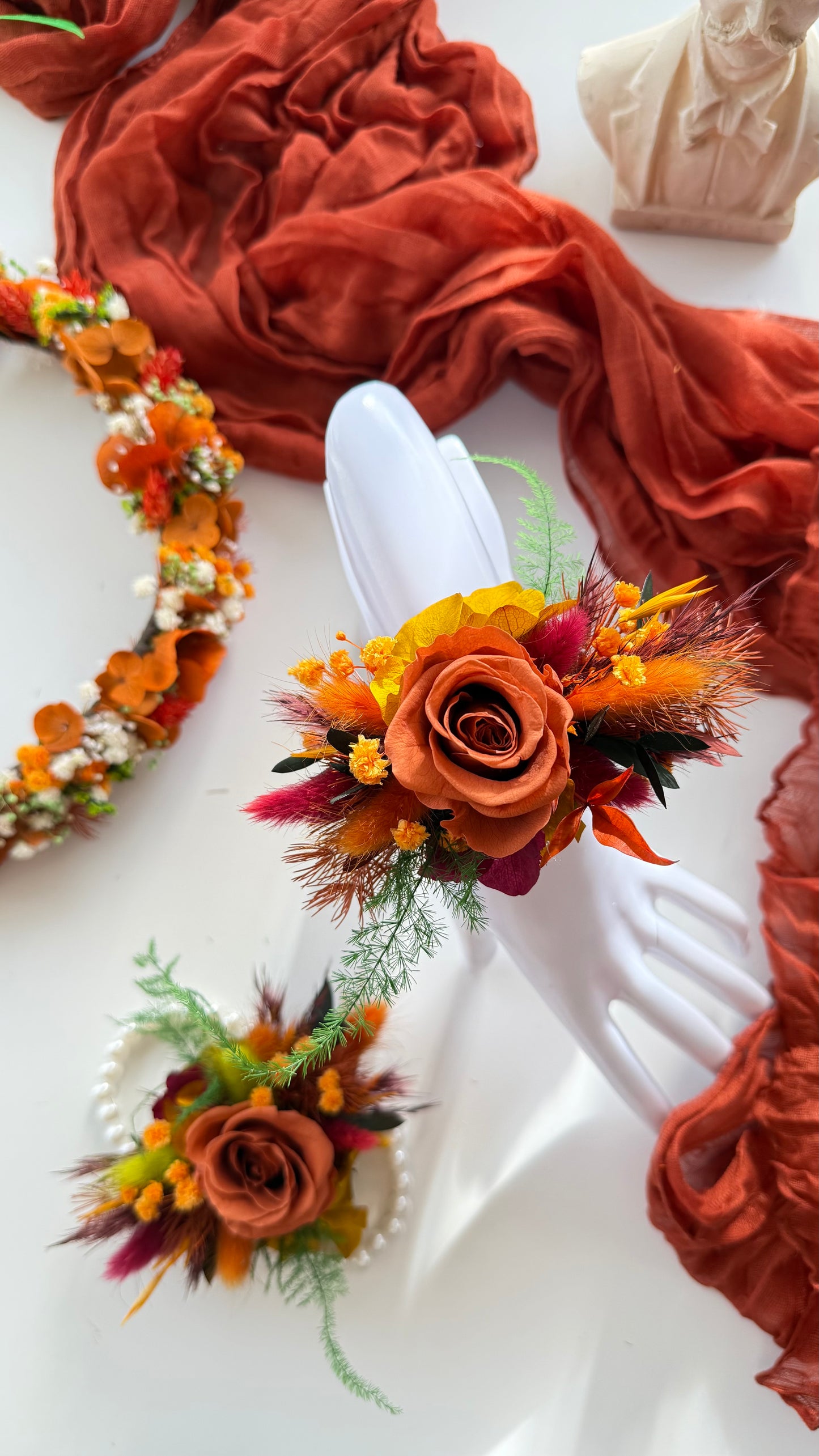 Decorative floral arrangements on white plates with a rust-colored fabric background