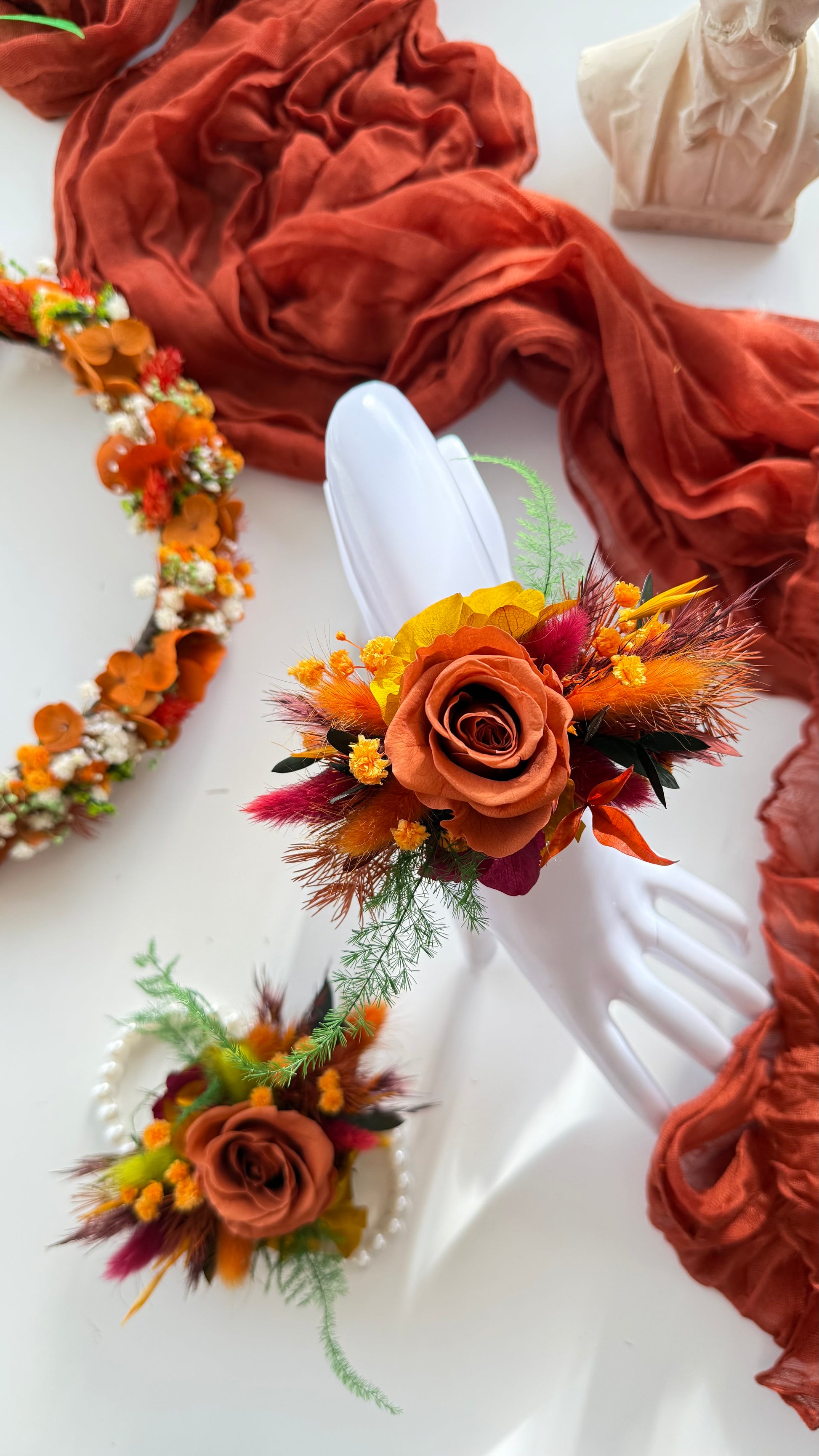 Decorative floral arrangements on white plates with a rust-colored fabric background