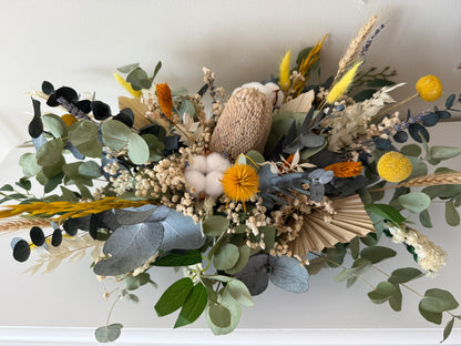 Dried floral arrangement with greenery and colorful flowers on a white background