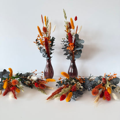 Two brown vases with dried floral arrangements on a white background