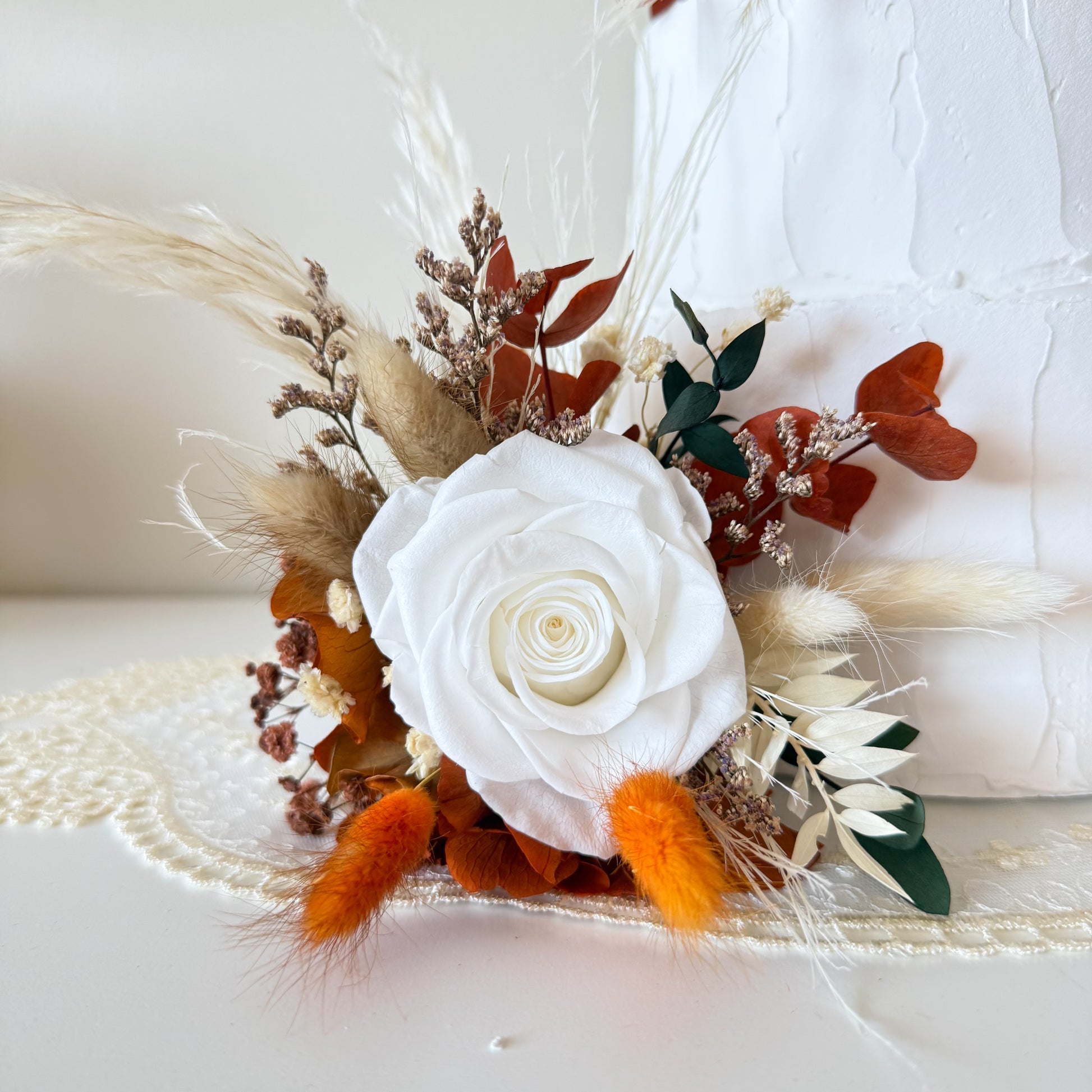 Terracotta and beige dried floral cake decoration with bunny tails and preserved botanicals on white cake