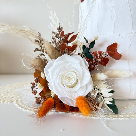 Terracotta and beige dried floral cake decoration with bunny tails and preserved botanicals on white cake