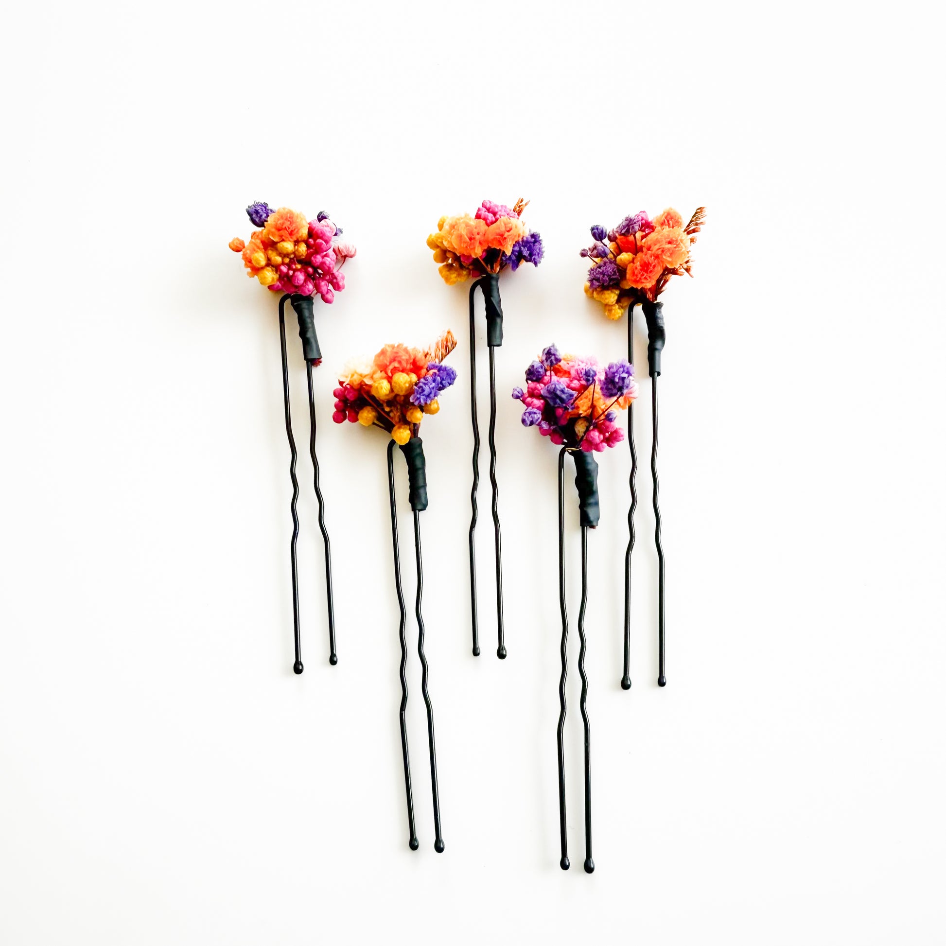 Five floral hairpins with colorful flowers on a white background
