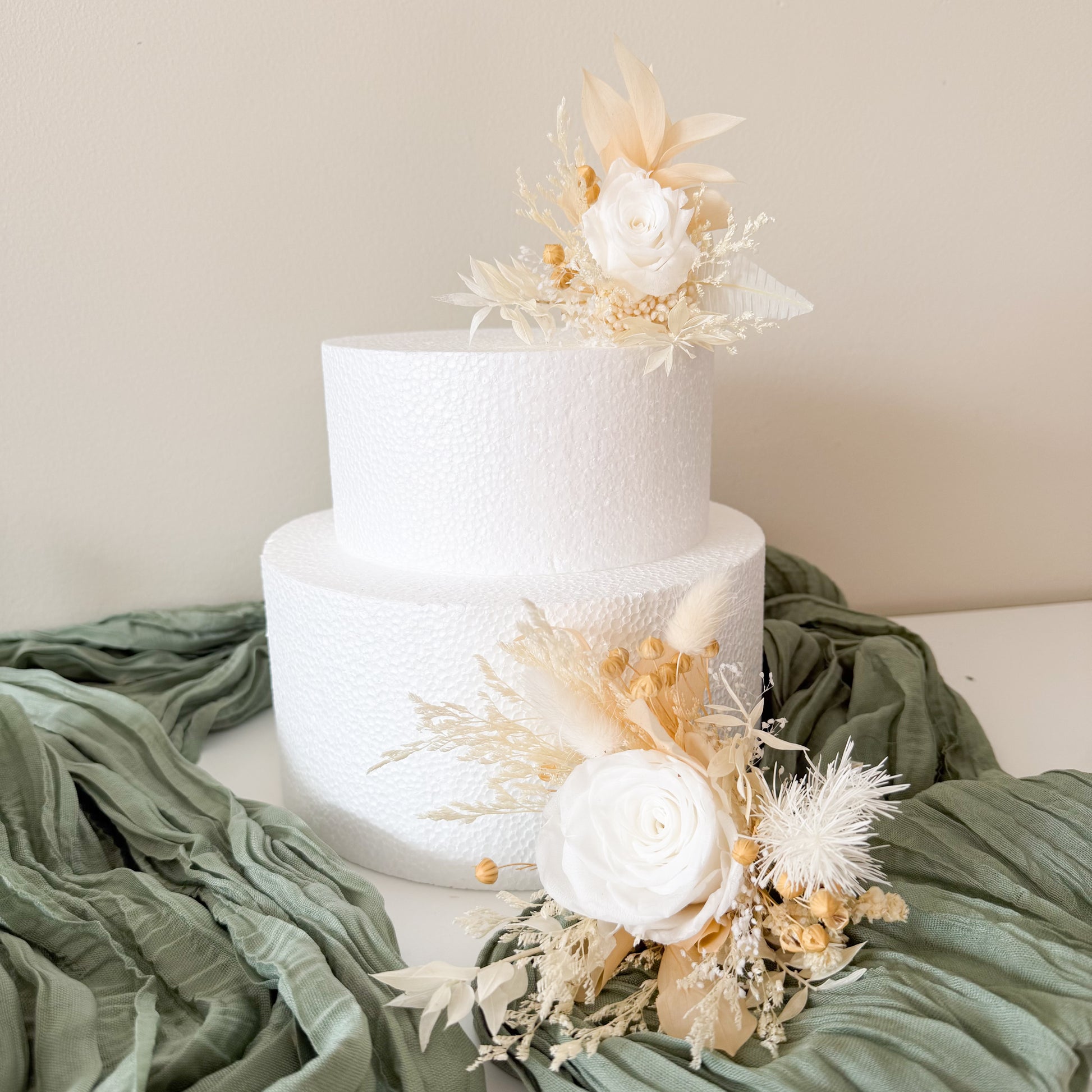 White wedding cake with floral decorations on a green fabric background