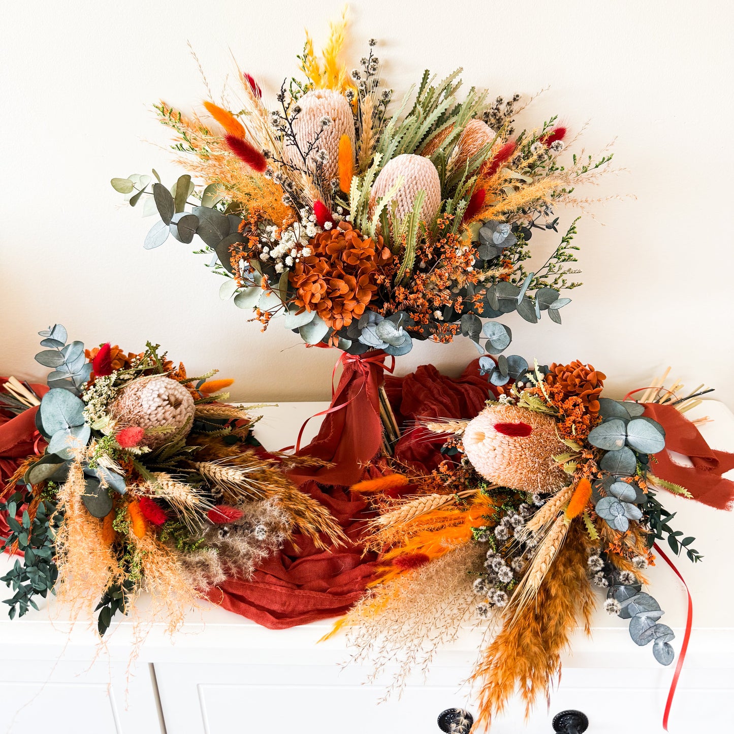Handmade boho rustic bouquet with preserved native flowers, tied with a bold red ribbon, perfect for Australian weddings.