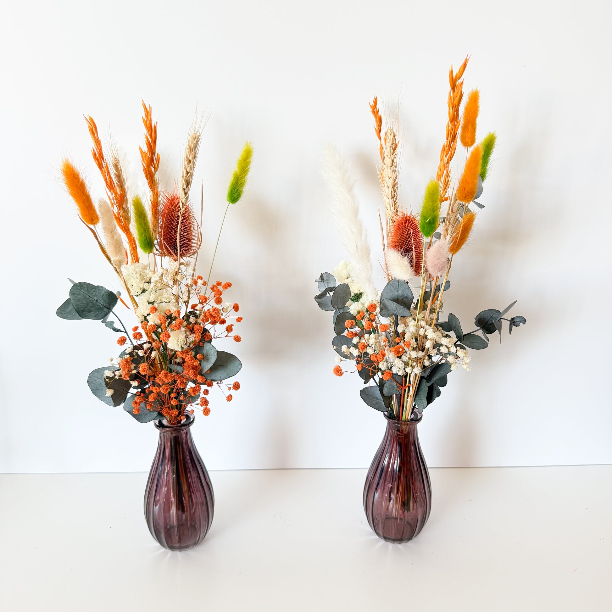 Flatlay of Australian dried flower arrangements in terracotta and orange shades with natural wheat and preserved eucalyptus
