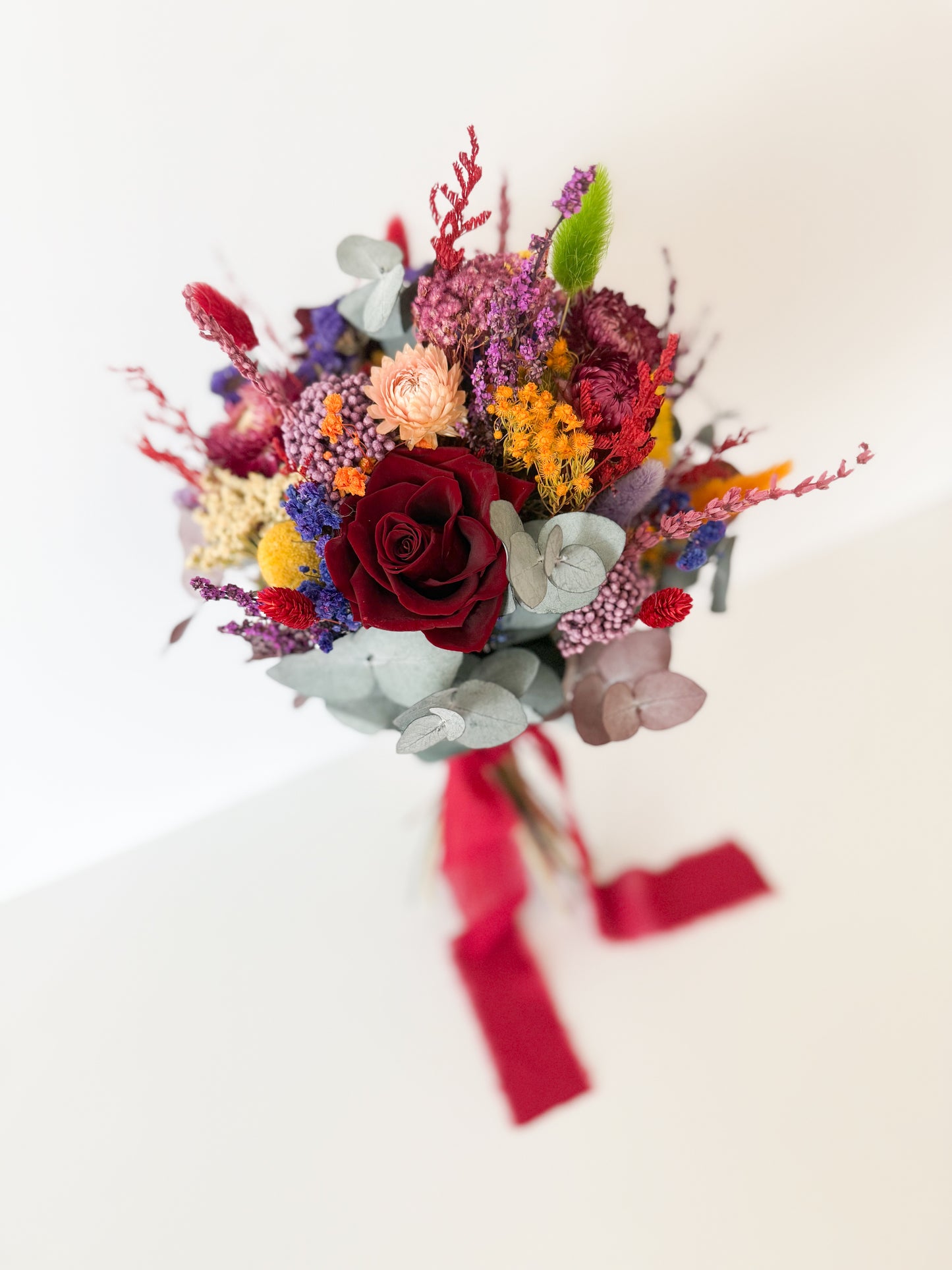 Australian dried wedding bouquet featuring preserved flowers in burgundy, coral, mustard, and lilac shades, ideal for rustic or bohemian weddings