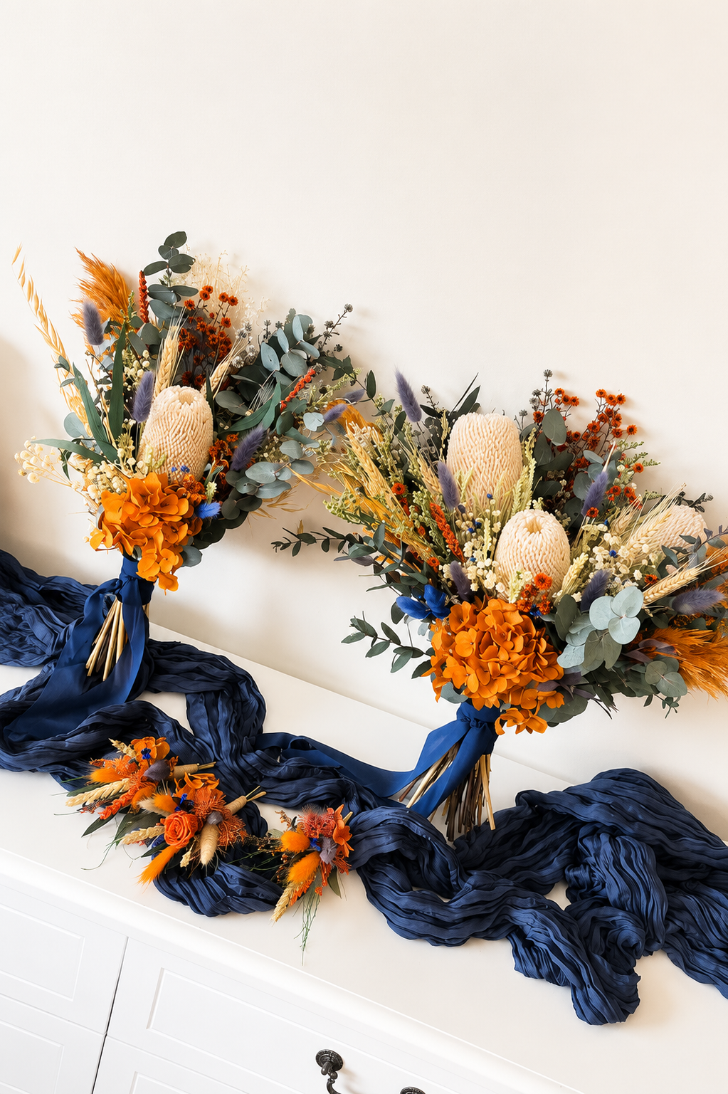Australian native bridal bouquet displayed with matching dried wedding boutonniere in burnt orange and navy blue colours