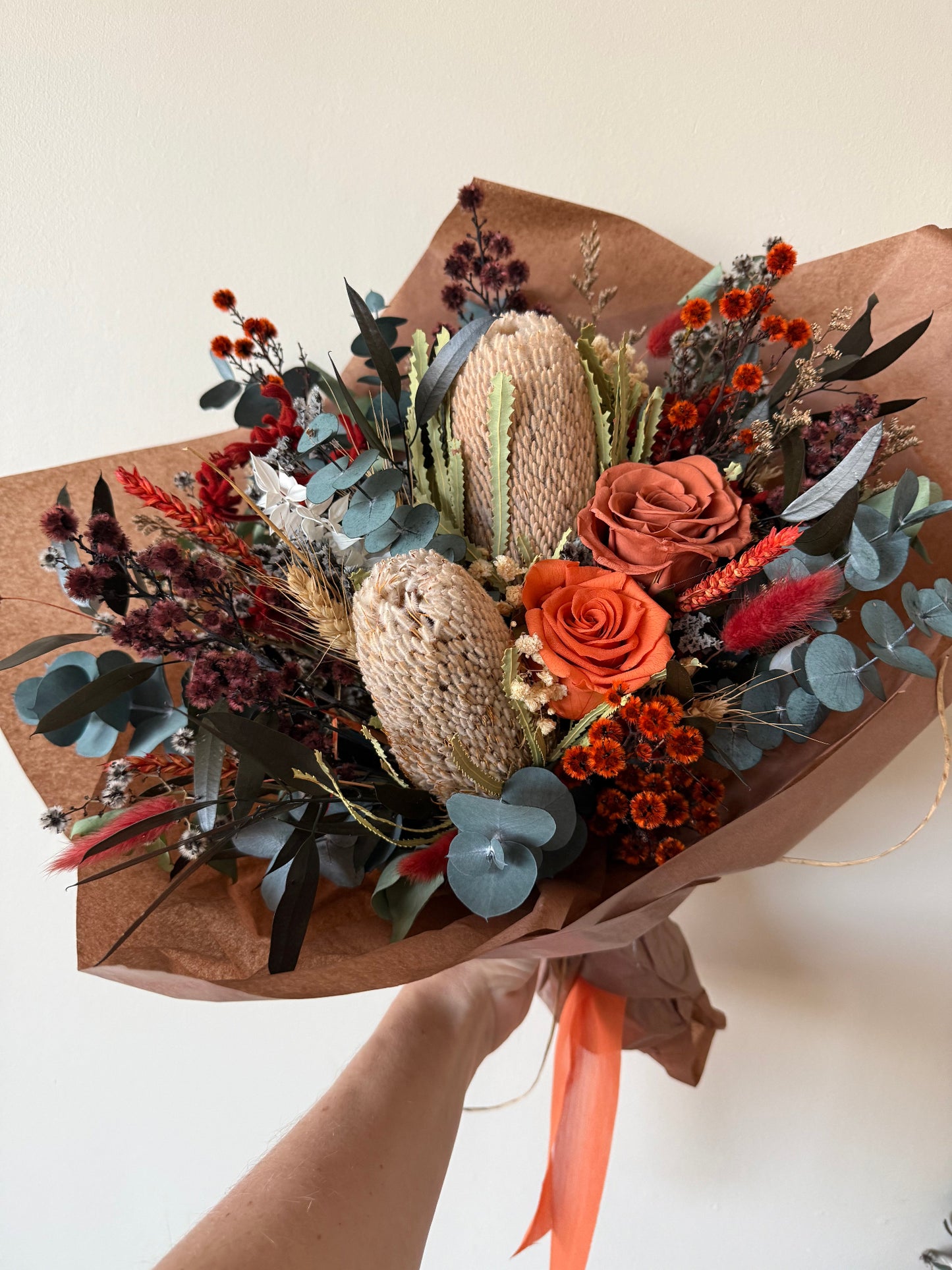 Australian native dried flower bouquet featuring banksia, preserved roses, eucalyptus and dried flowers in terracotta, rust and sage tones, beautifully gift wrapped for delivery in Australia