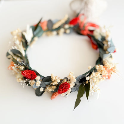 Floral wedding hair wreath with red flowers and green leaves on a white background