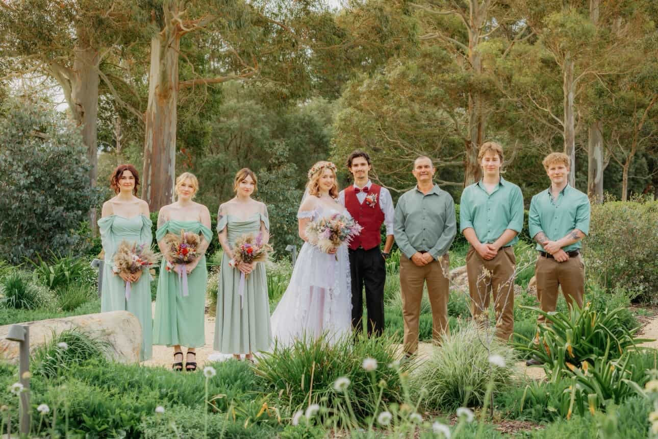 Bridal party standing outdoors at an Australian wedding, with bridesmaids holding matching dried flower bouquets in soft natural tones.