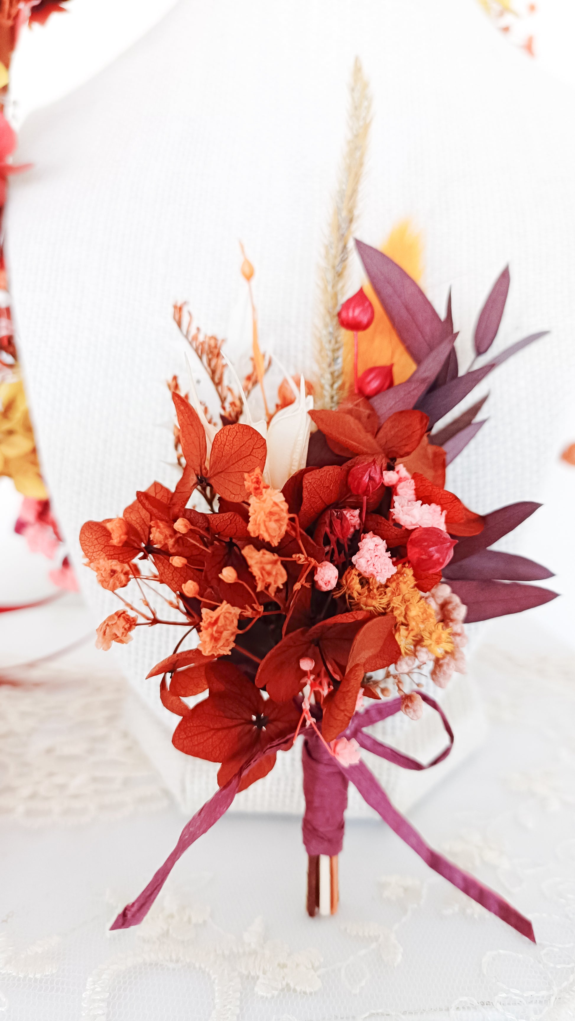 Boho-style boutonniere with dried flowers in shades of pink, red, and yellow, designed for brides, bridesmaids, or vintage-inspired looks. Unique, handmade floral hair accessories.