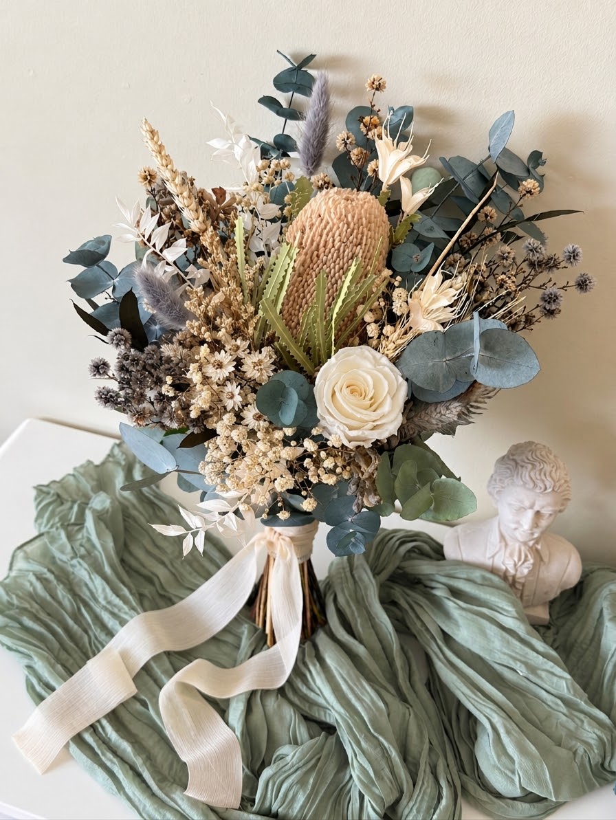 Dried bridal bouquet with natural Banksia, blue-green preserved eucalyptus, ivory rose and Australian native flowers.