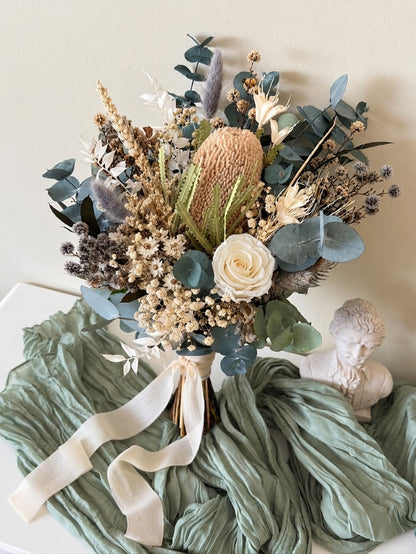Dried bridal bouquet with natural Banksia, blue-green preserved eucalyptus, ivory rose and Australian native flowers.