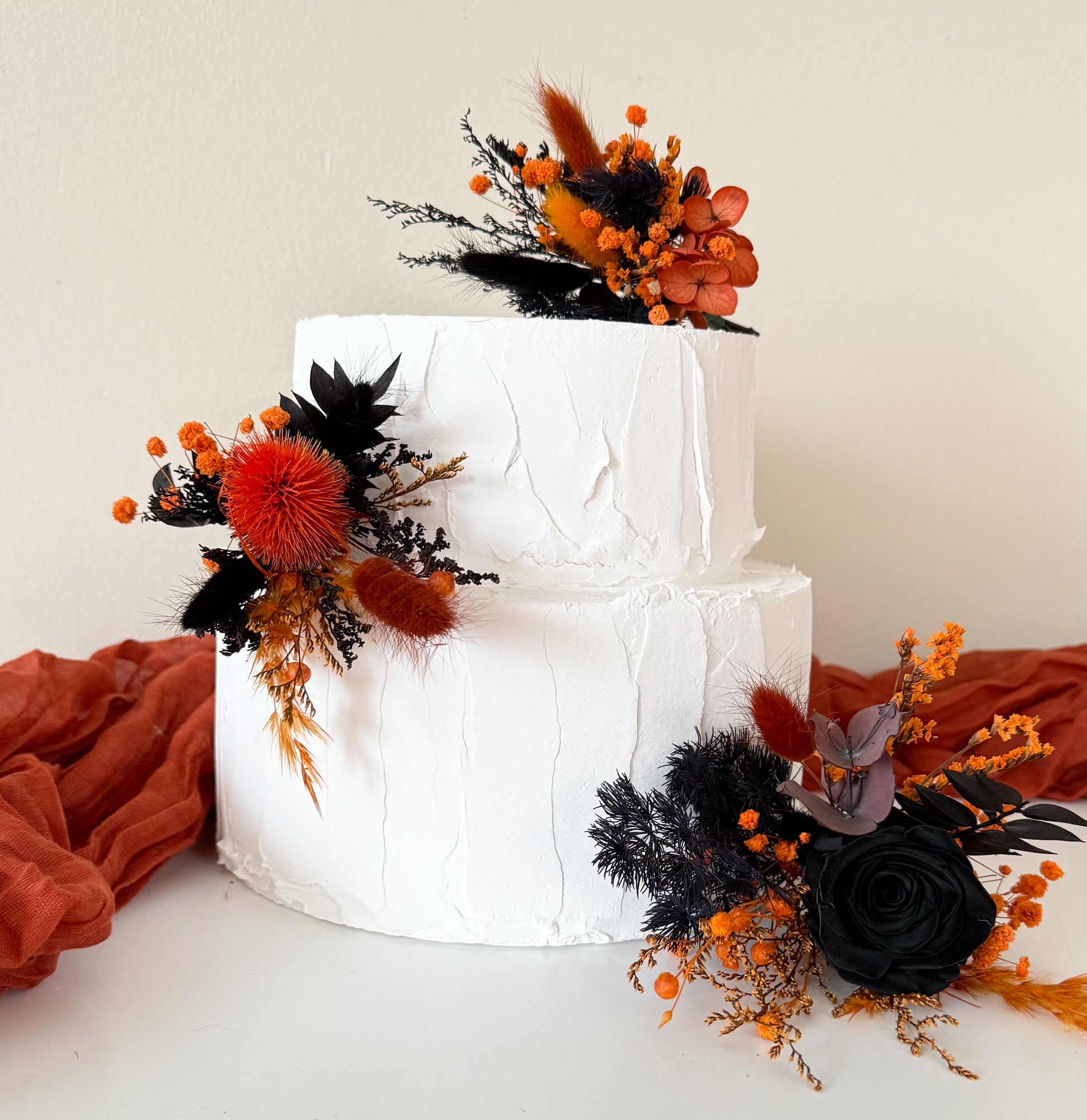 Black and burnt orange dried flower cake topper with preserved roses, thistle and bunny tails