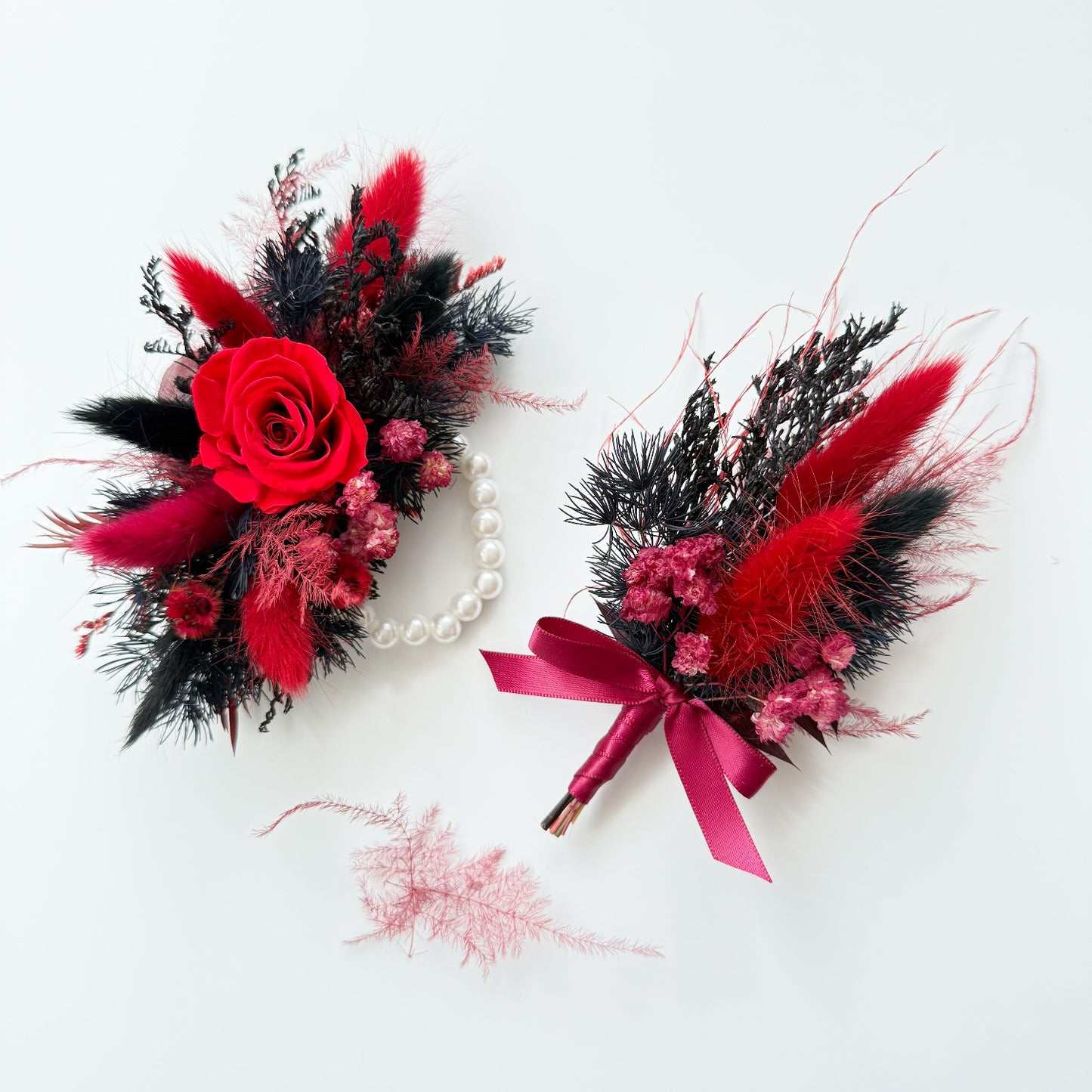 Two floral accessories with red, black, and pink flowers on a white background