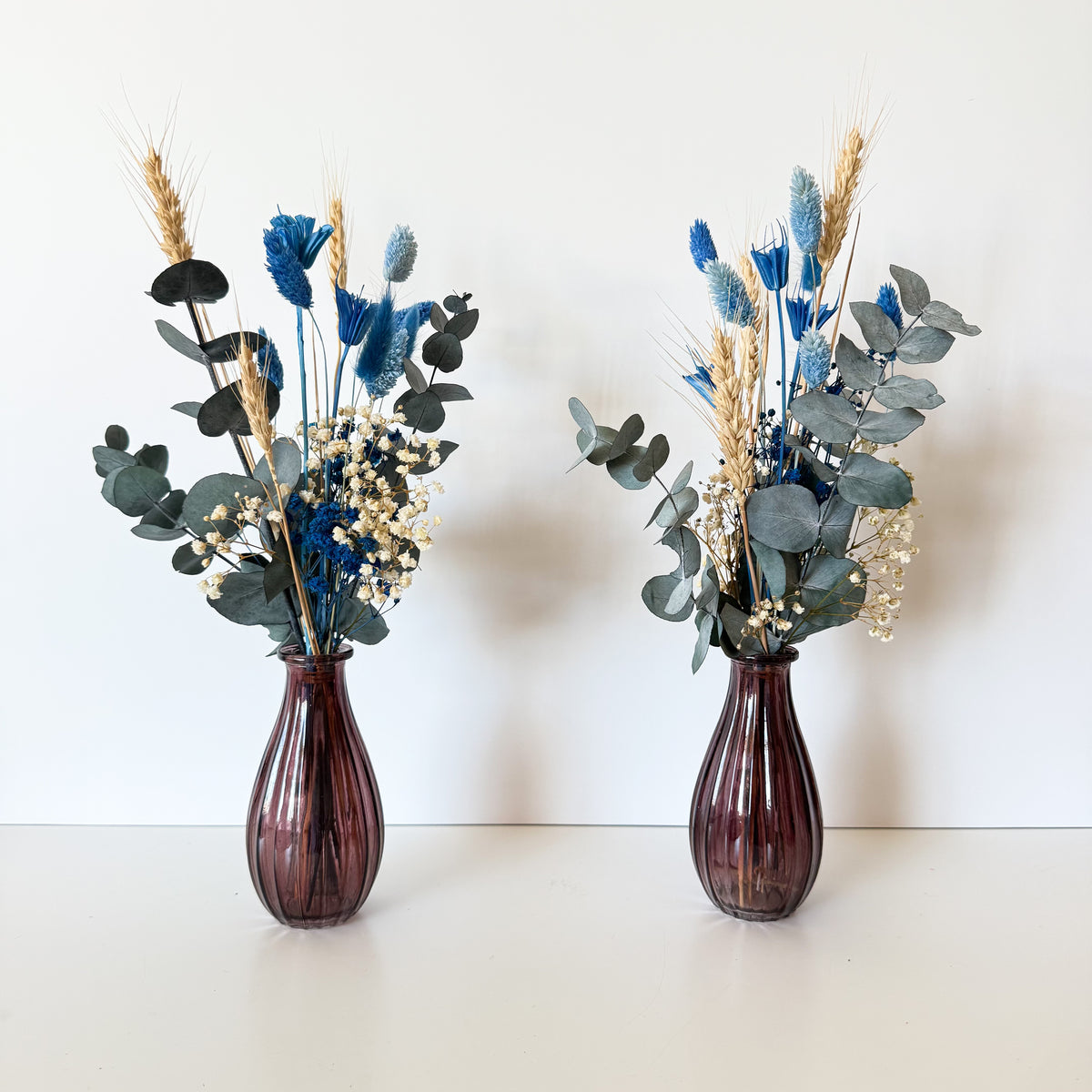 Blue and ivory dried flower bud vase arrangements with preserved eucalyptus and natural grasses for wedding table decor