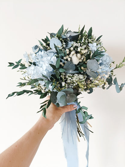 dusty blue wedding bouquet, blue and white bridal bouquet, soft blue floral arrangement, light blue preserved flowers, pastel blue bouquet, rustic blue wedding bouquet, boho blue bridal bouquet, elegant blue and white bouquet, romantic wedding bouquet, vintage-inspired bouquet, medium bridal bouquet, hand-tied wedding bouquet, loose organic bouquet, blue wedding theme, dusty blue wedding inspiration, rustic boho wedding flowers, elegant blue and white wedding, classic blue wedding bouquet