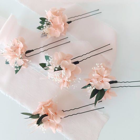 Set of blush peach dried flower hair pins for brides or bridesmaids, styled on soft pink fabric