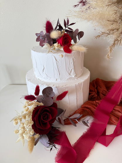 Elegant wedding cake decorated with burgundy roses, ivory dried blooms and preserved foliage