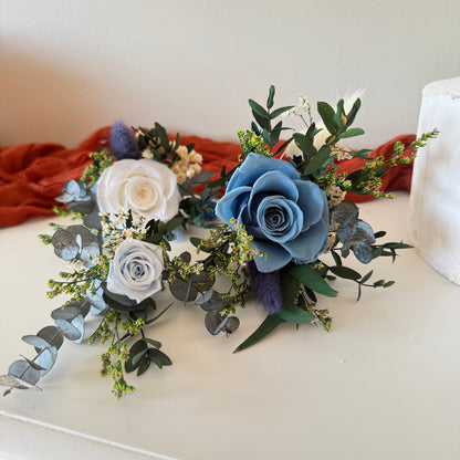 Boho cake flower decorations combining soft blue roses, ivory flowers and natural preserved greenery, designed for an earthy wedding celebration.