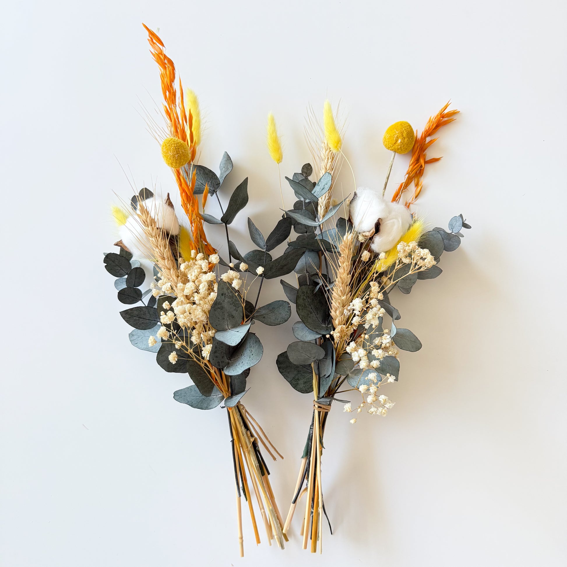 Pair of boho-style dried flower bouquets in yellow and white shades with preserved eucalyptus and natural textures.