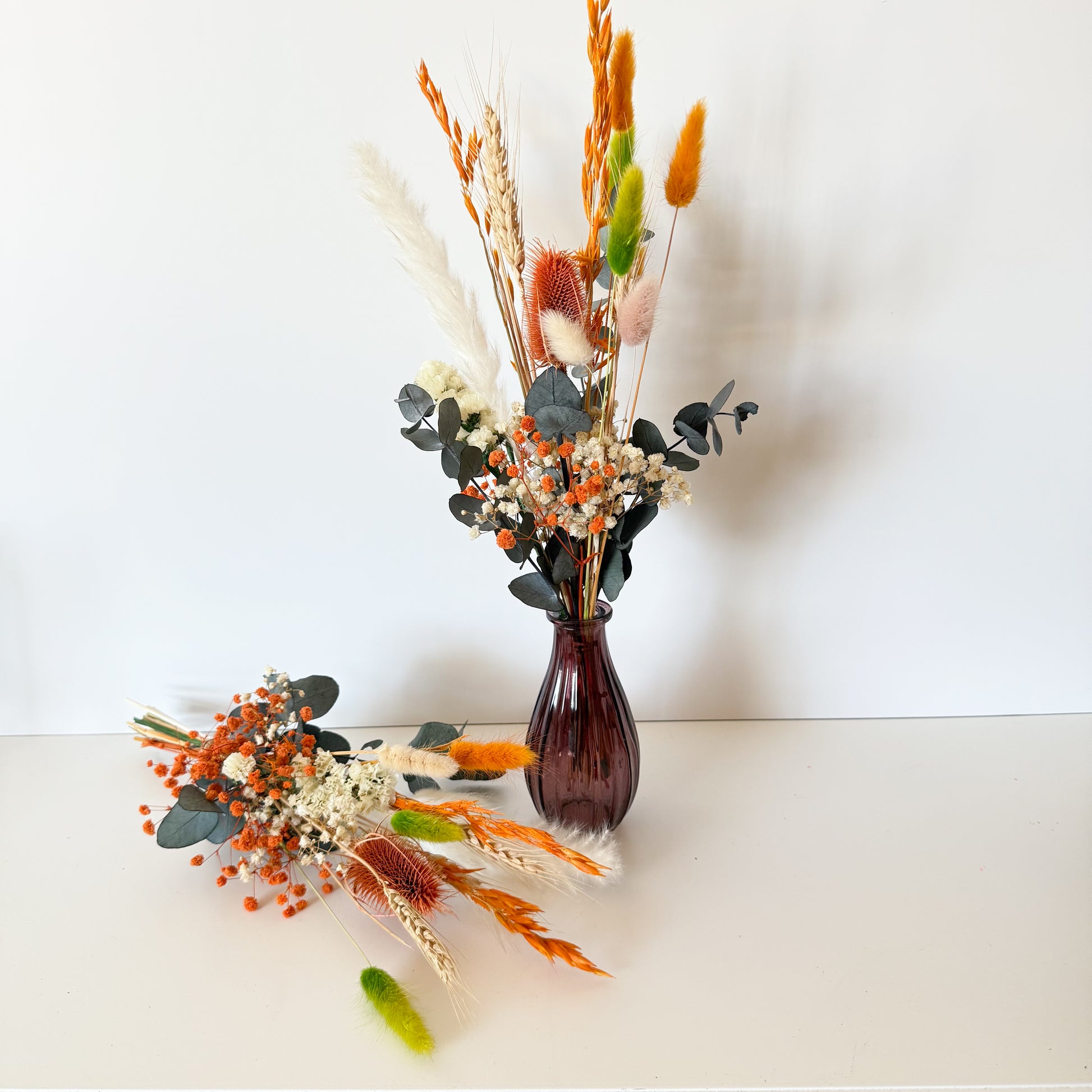 Boho vase decor featuring orange, ivory, and green dried flowers with eucalyptus, perfect for rustic or autumn styling