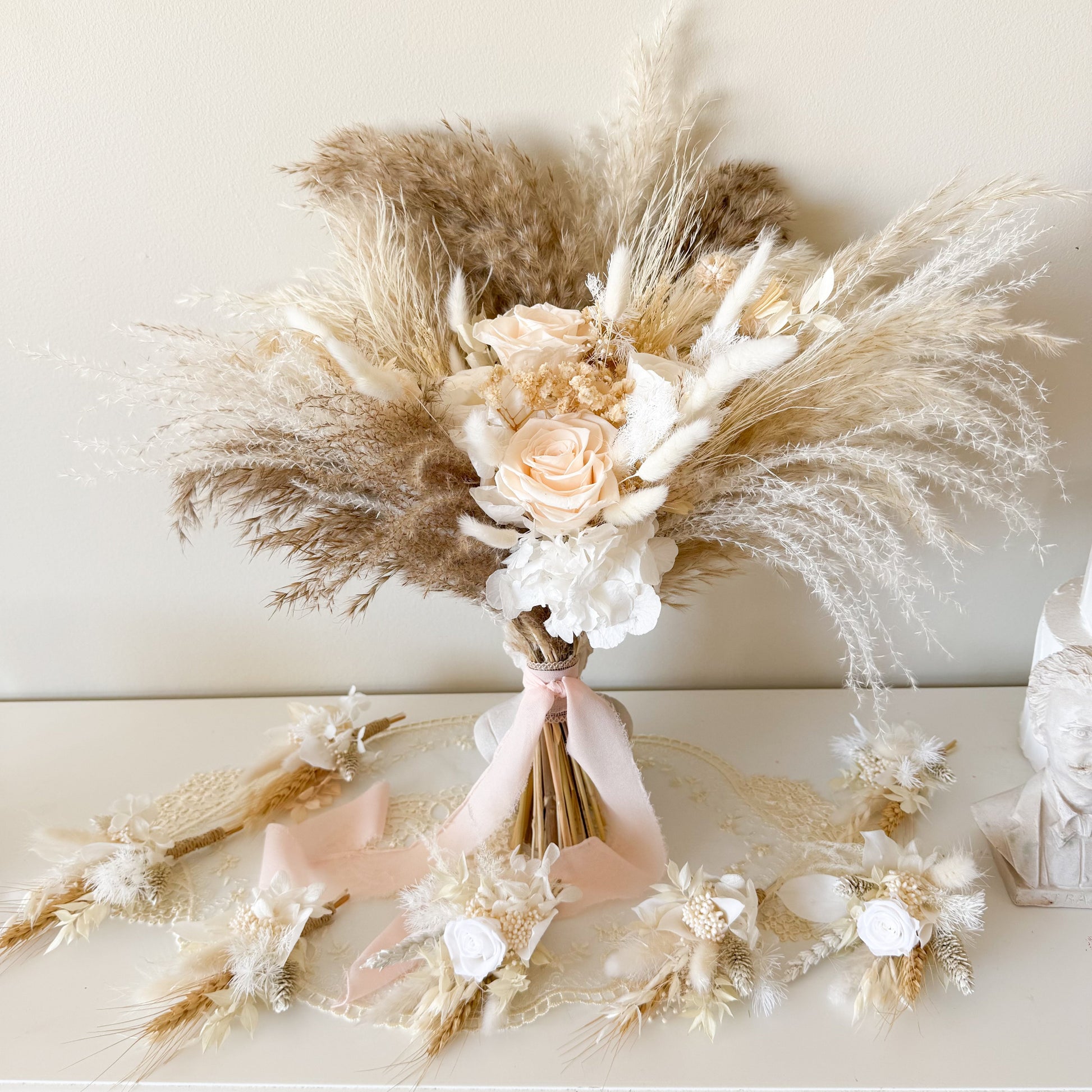 Bouquet of dried flowers and pampas grass on a white surface with a neutral background