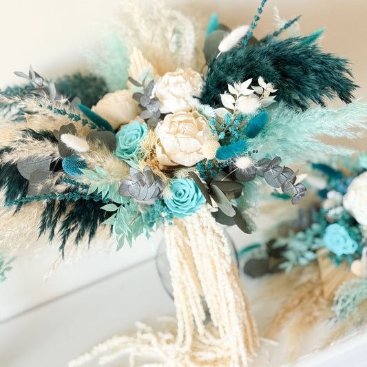 bridal dried arrangement with teal, beige, and gray flowers on a neutral background