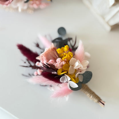 Floral boutonniere with pink, yellow, and white flowers on a light background