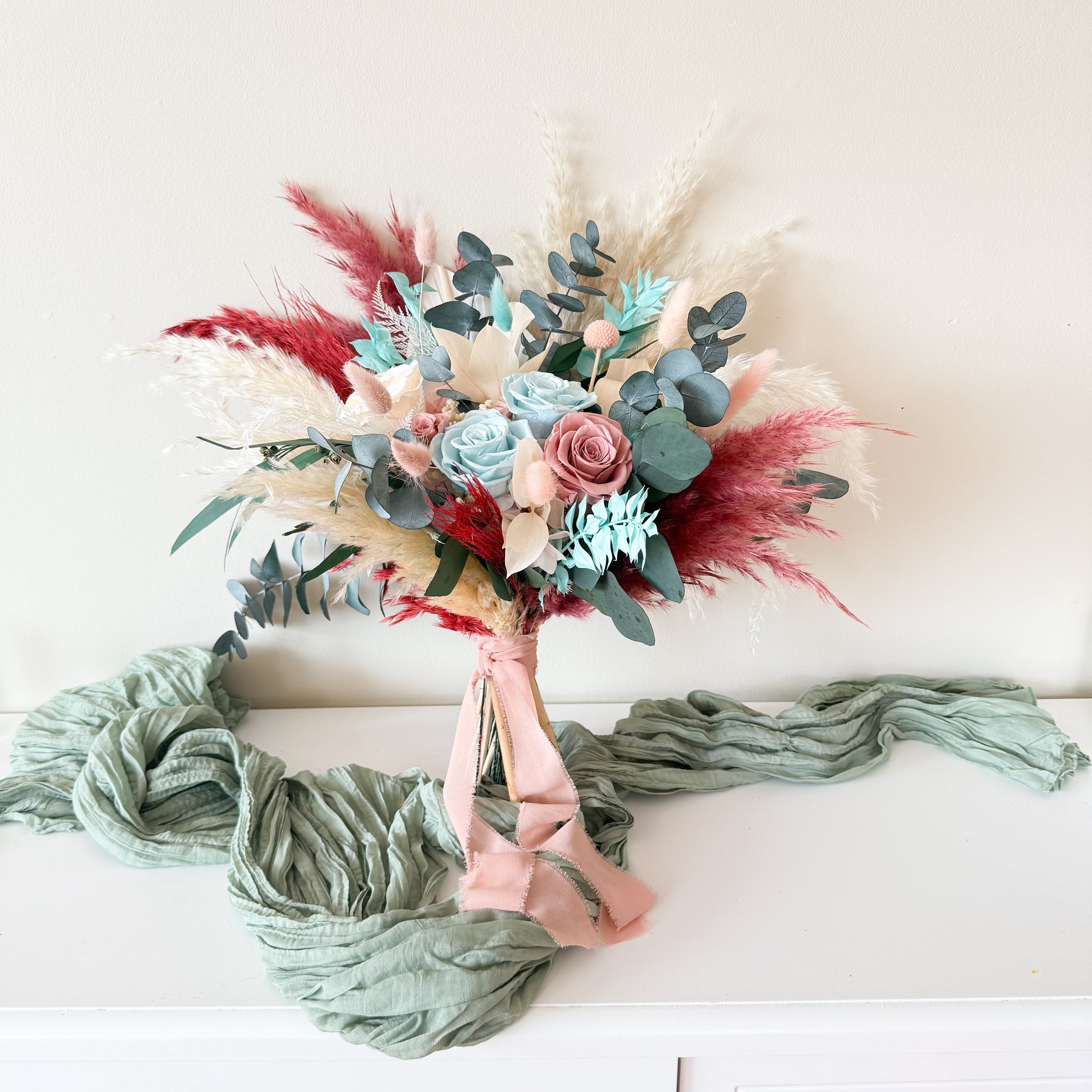 Boho coastal wedding bouquet with seafoam and blush preserved roses, fluffygrass, and eucalyptus leaves