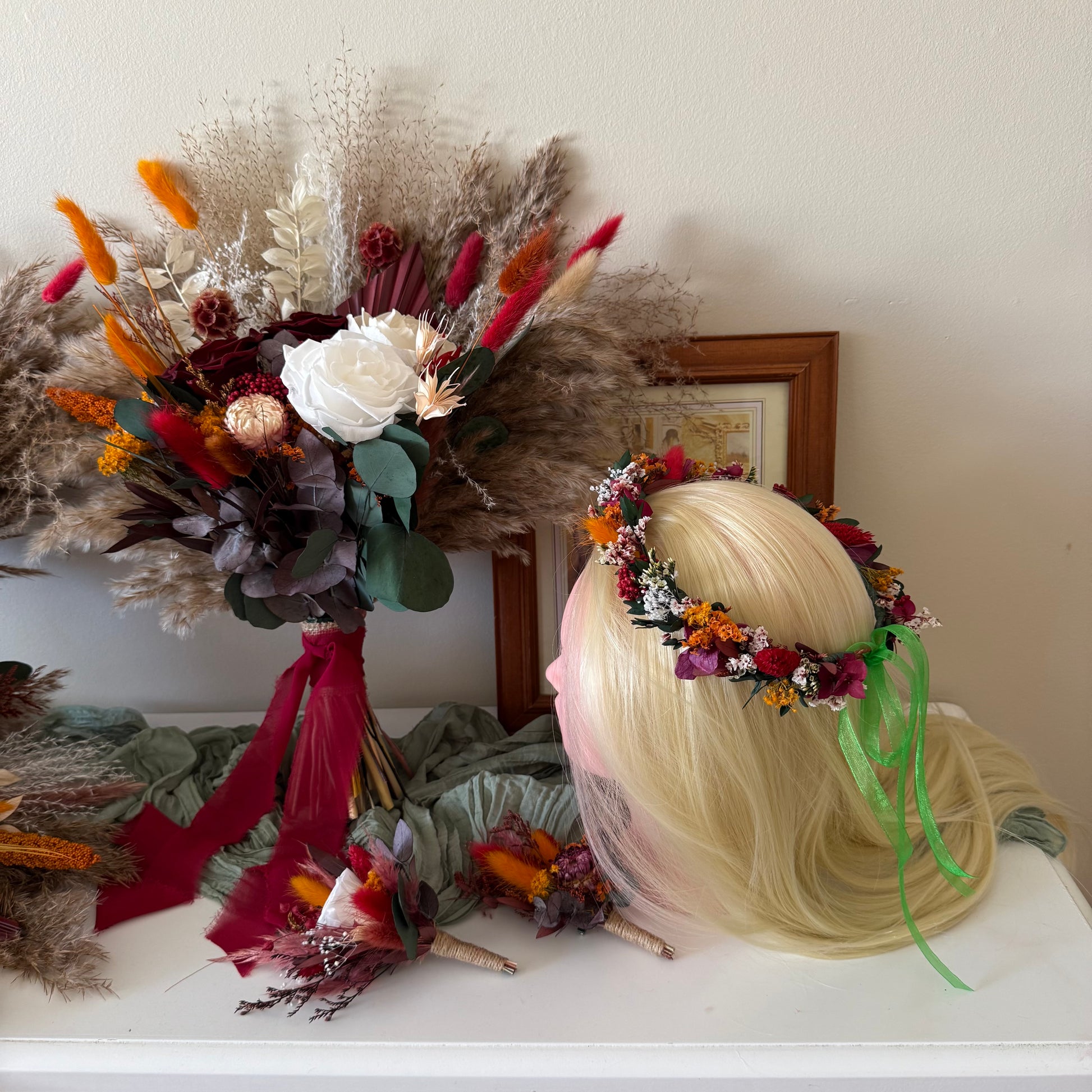 Bouquet of flowers and a head with a floral crown on a white surface.