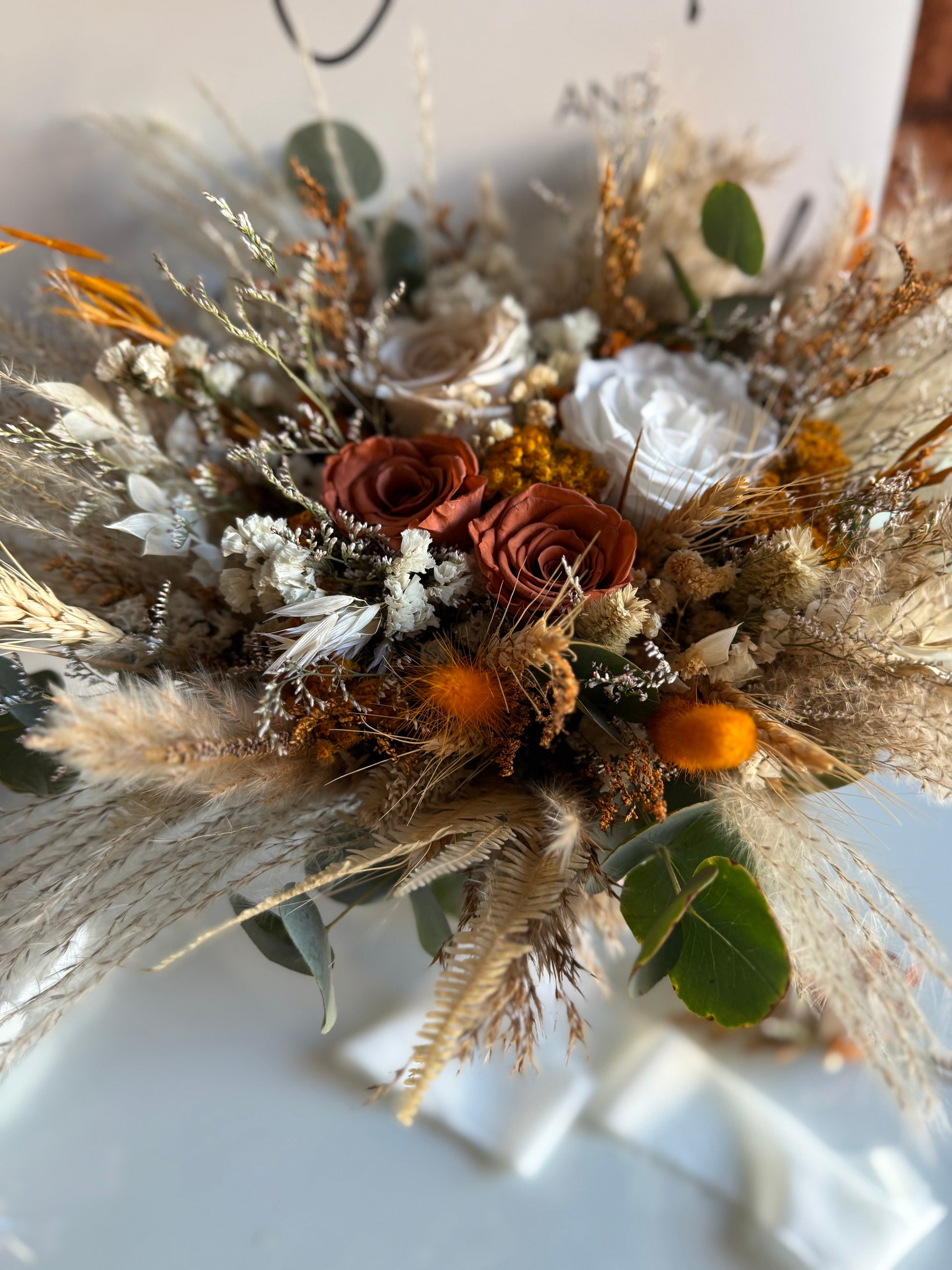 Dried floral arrangement with brown, orange, and green colors 