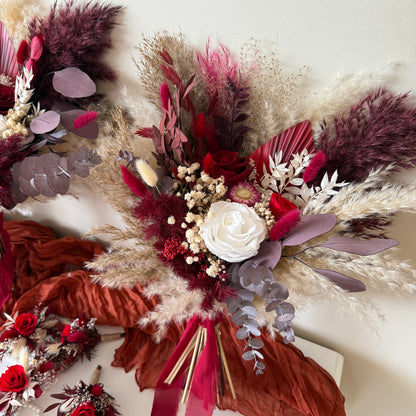Bridesmaid bouquet in burgundy and ivory dried flowers with pampas grass, eucalyptus, and sola wood roses.