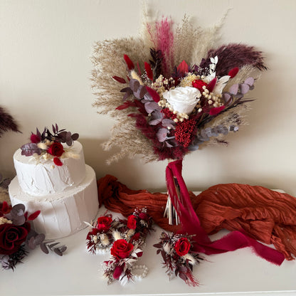 Two-tier white cake with burgundy dried flower topper and matching bouquet in boho rustic style