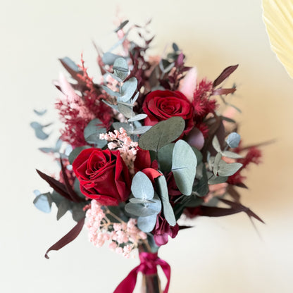 Close-up of burgundy preserved roses and dried flowers in wedding bouquet